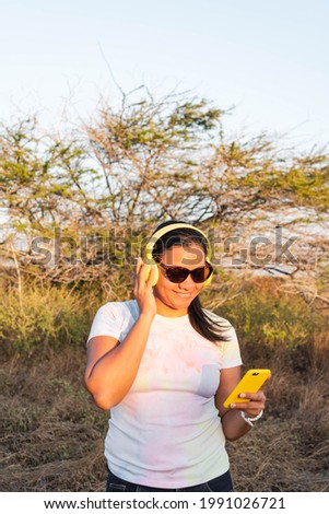 Smiling latina woman using cell phone in the field