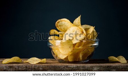 Potatoes Chips. Chips in glass bowl good for snack for beer or ale on natural wooden table. Good for beer festival, pub, restaurant advertising. Food and Drink photography. Macro high resolution Photo Royalty-Free Stock Photo #1991027099