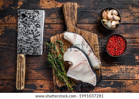 Blue Shark raw fish steaks on a cutting board with cleaver. Dark wooden background. Top view