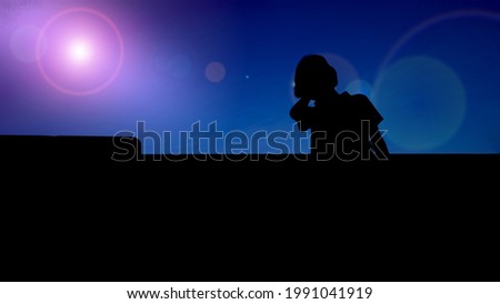 Silhouette of nonbinary person looking up against blue background with lens flare effect