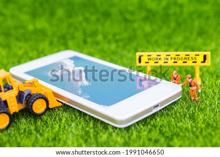 Smartphone repair and maintenance service, technology and communication concept, phone and miniature worker with road sign on green grass background
