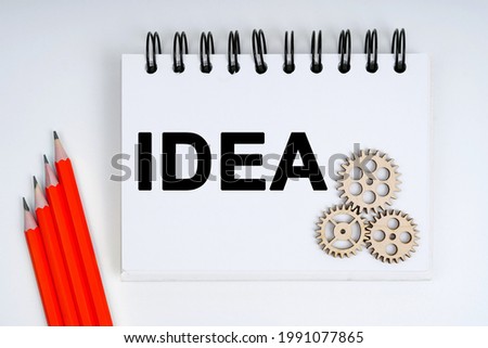 Business and finance concept. On a white background, there are red pencils, gears and a notebook with the inscription - IDEA