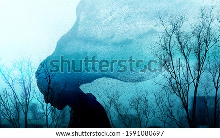 Mental Health Disorder Concept. Exhausted Depressed Female. Silhouette of Stressed Woman combined with Dry Tree and Rain. Depression Psychology. Dark Blue Tone Royalty-Free Stock Photo #1991080697