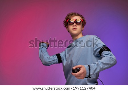 amazed boy trying augmented reality glasses, feeling excited about VR headset simulation and controllers, exploring virtual life by gesturing hands to touch 3d world, having fun with goggles