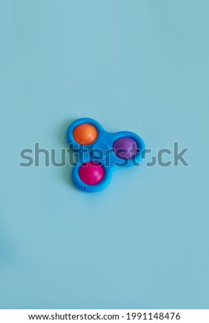  Silicone Toy Spinner Simple Dimple. Blue background. Vertical format. Copy space 
