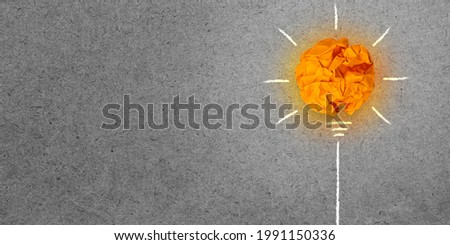 Orange crumpled paper light bulb on grey board background,  Think idea business and environmental concept with copy space.