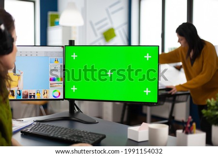 Woman retoucher working on photo set in photo editing software using greenscreen, chroma key isolated display of computer. Content creator doing portrait retouching in digital multimedia company