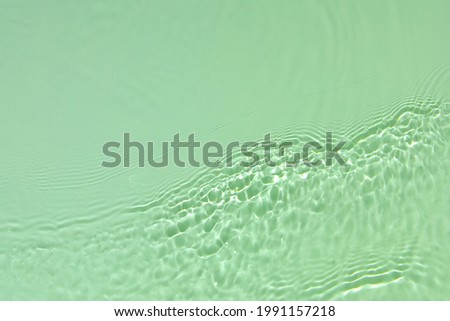 Green transparent clear water surface texture with ripples, splashes and bubbles Abstract summer nature background Mint colored waves in sunlight with copy space Cosmetic moisturizer micellar emulsion