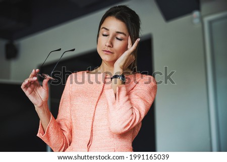 Beautiful elegant Caucasian woman in formal wear feeling headache in the meeting room