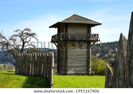 A reconstructed wooden Roman watchtower and a wooden border fence under a clear blue sky. This fortification was part of the "Limes", the border of the former Roman Empire. Royalty-Free Stock Photo #1991167406