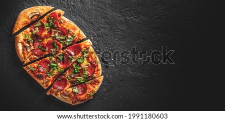 flatbread Pepperoni Pizza with Mozzarella cheese, salami, Tomato sauce, pepper, Spices. Italian pizza on Dark grey black slate background Royalty-Free Stock Photo #1991180603