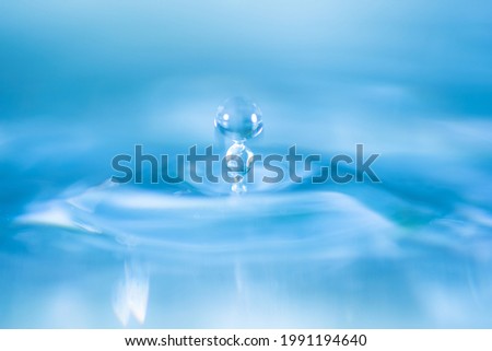 water drop splash in a glass blue colored shot of water that is dripping and reflecting water.
