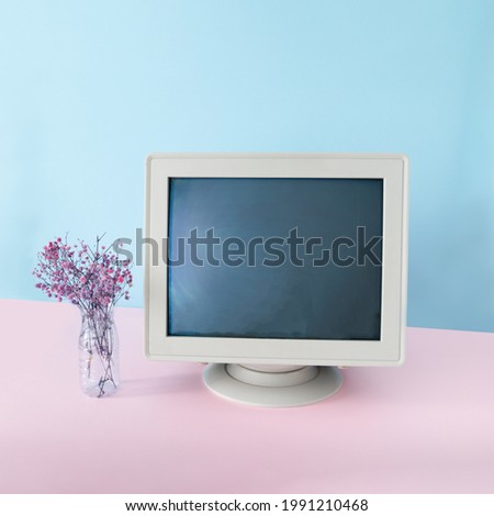 Retro vibe with old crt monitor and a bouquet of pink flowers on a pastel pink , blue background.Creative copy space.