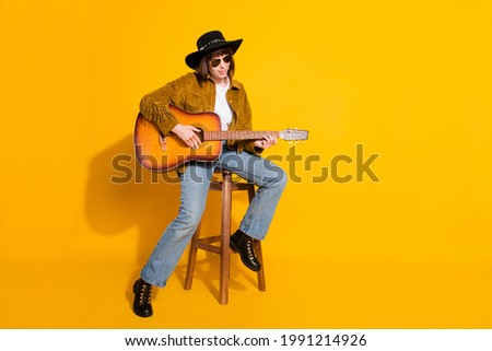 Photo of pretty adorable lady wear cowgirl outfit glasses headwear playing guitar singing empty space isolated yellow color background Royalty-Free Stock Photo #1991214926