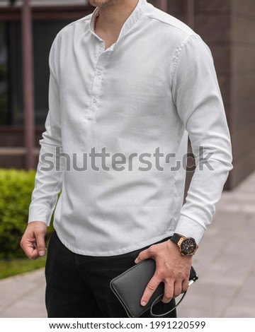 Stylish handsome model man in casual clothes lifestyle in the street with watch and leather clutch Royalty-Free Stock Photo #1991220599