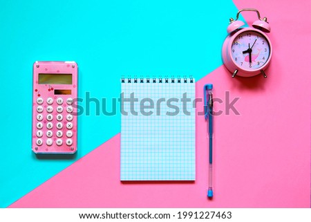 Back to school concept. Trendy mint pink background. On a colored background, an alarm clock, a calculator, a notebook and a pen