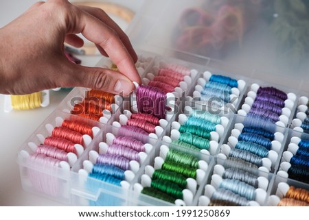 Close up oа colorful embroidery floss bobbins in the box. Embroidery threads and tools for handmade, crafts, hobbies. Royalty-Free Stock Photo #1991250869