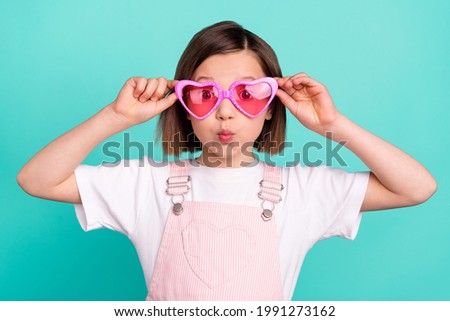 Photo of pretty cute schoolgirl dressed pink overall arms eyewear big eyes lips pouted isolated turquoise color background