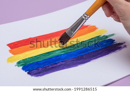 hand with brush draws rainbow multicolored strokes, lgbt symbol concept, gay pride color, paint drawing