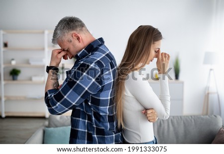 Mature married woman and her husband standing back to back, having relationship problems, thinking about divorce or breakup at home. Middle-aged spouses going through marital crisis Royalty-Free Stock Photo #1991333075