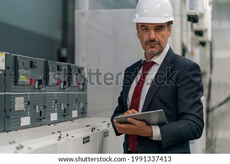 Portrait shot of senior engineer or management inspecting work in the electrical control room .Industrial quality work business concept. Royalty-Free Stock Photo #1991337413