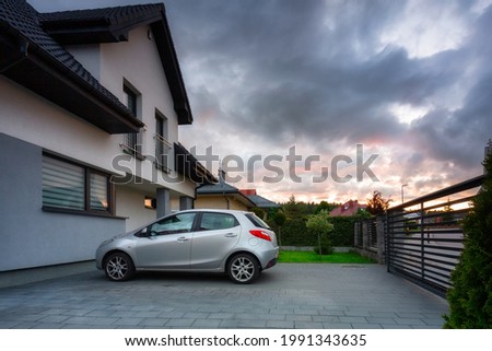 A modern single family house with a car parked outside at sunset Royalty-Free Stock Photo #1991343635