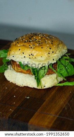 Salmon burger grilled with basil leaves and caesar sauce