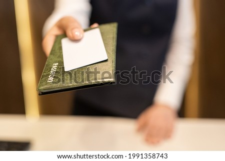Hand of female receptionist passing passport and white blank plastic card