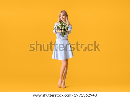 Beautiful young woman with bouquet of roses on color background