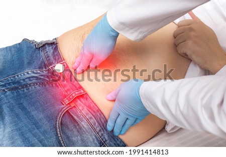The surgeon performs a finger examination of a patient who has pain around the navel. Umbilical hernia disease concept, umbilical hernia removal, close-up Royalty-Free Stock Photo #1991414813