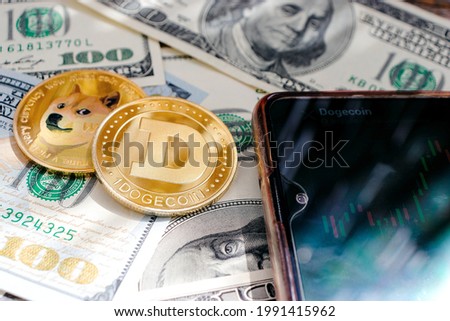 Dogecoin in close-up on the background of dollar bills, phone with graph, sun rays Royalty-Free Stock Photo #1991415962