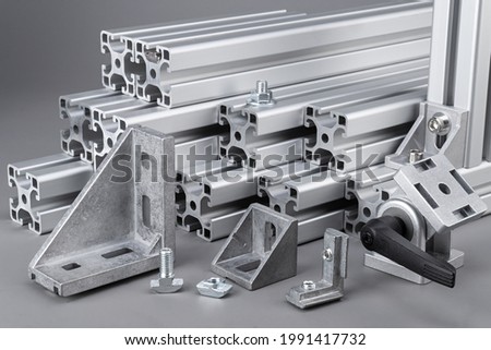 Aluminum exstrusion profile bars with accessories corner angle and screws on gray background. construction industry engineering and material concept. Royalty-Free Stock Photo #1991417732