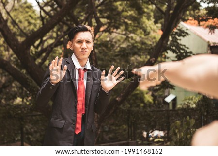 A young university student denies accusations made against him. The pointing hand of the accuser visible in photo. Royalty-Free Stock Photo #1991468162