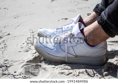 Vacation holidays. Close up of mans feet relaxing by the sea. White snikers Royalty-Free Stock Photo #1991484986