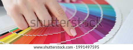 Designer holding color swatch at desk in office closeup