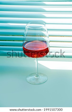 Still life with red refreshing summer alcoholic cocktail drink with strawberry in wine glass on blue background. Fruit or berry wine. Minimalism