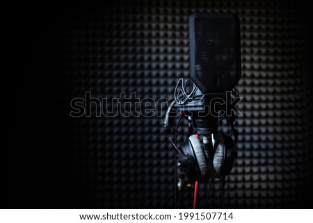 Professional studio condenser microphone in recording studio with studio headphones on a sound acoustical foam Background in record room