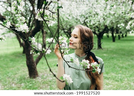young beautiful girl in a green dress in the blooming gardens of the park