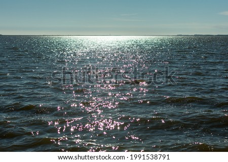 Sun glare in waves of sea water on a tropical beach in summer in nature close-up. Beautiful texture of water waves.Sea wave and sand seashore. Golden sun light over the sea ocean waves
