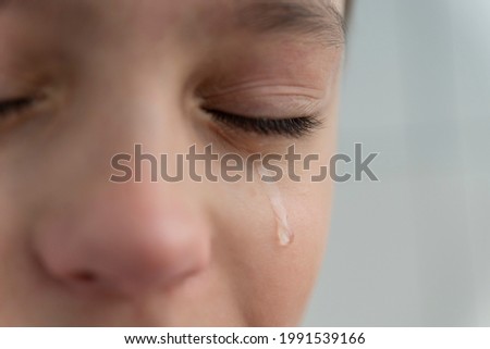 Tear rolls down the boy's cheek, his eyes are closed, he is upset and crying. Sad, unhappy emotions of child. Royalty-Free Stock Photo #1991539166