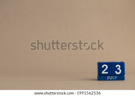 Date 23 July on blue cubes on a beige eco background