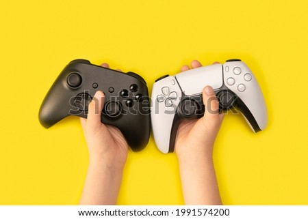 Kid holding game controllers in yellow background Royalty-Free Stock Photo #1991574200