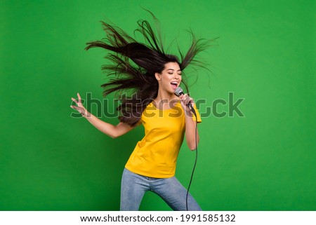 Photo portrait of overjoyed girl with long brunette hair singing karaoke at party isolated vibrant green color background