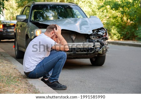Car accident. Man holding his head after car accident. Man regrets damage caused during car wreck. Man driver is indignant had an accident on road. Headache injury blow to head. Royalty-Free Stock Photo #1991585990