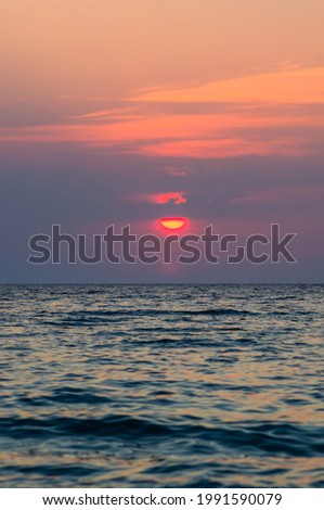 Summer sea sunset on the pebble beach, the sun, waves and clouds, beautiful dramatic lighting
