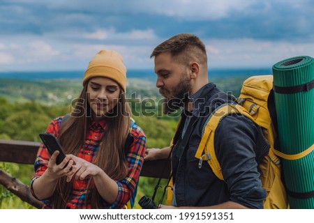 Young couple of hikers using smartphone while trying to find out their location while enjoying the day in the nature
