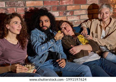 Bored Guy Sleeping While Diverse Friends Watching Movie Online On TV, At Home, Sitting On Sofa, At Night, Fall Asleep During Movie