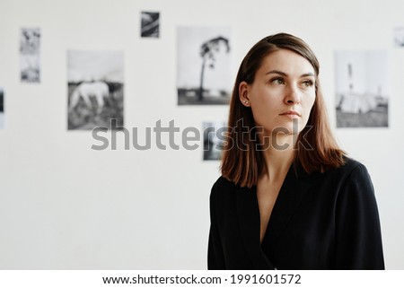 Graphic portrait of elegant young woman wearing black in modern art gallery, copy space