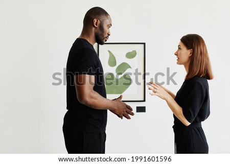 Minimal waist up portrait of elegant couple discussing paintings in modern art gallery, copy space