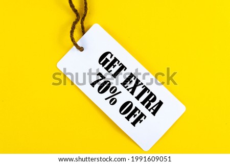 GET EXTRA 70 OFF percent text on a white tag on a yellow paper background